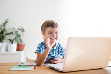 Çocuk bir dizüstü bilgisayar kullanıyor ve evdeki video öğretmeniyle internetten ders çalışıyor. Evde eğitim, uzak öğrenim