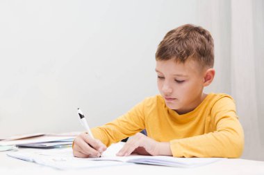 Okullu çocuk ders alıyor ve evdeki defterlere ödevler yazıyor. Evde eğitim, evde uzaktan öğrenim.. 