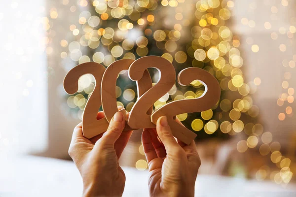 在圣诞装饰的背景下 女性的手捧着2022号数字 免版税图库图片