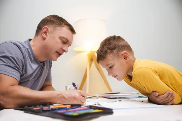 爸爸帮助儿子做功课 在家学习 远距离学习 图库图片