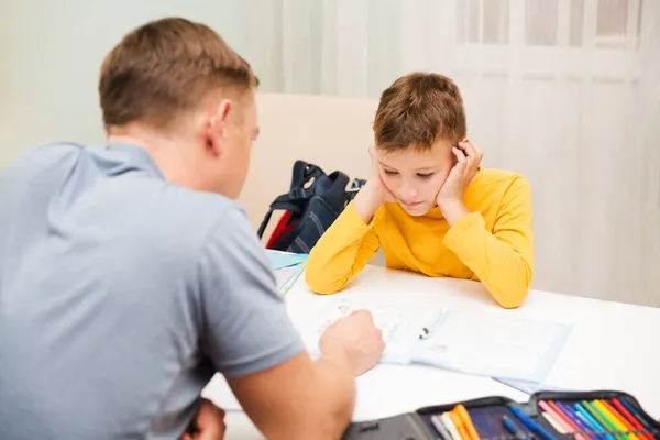 爸爸帮助儿子做功课 在家学习 远距离学习 免版税图库图片