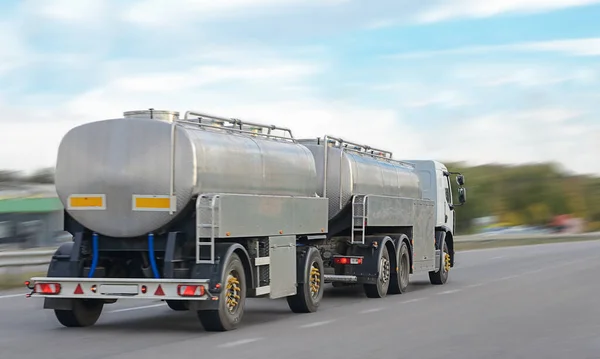 Büyük gri tank kamyonu, mavi gökyüzüne karşı güneşli bir günde sağ şeritte dikiz manzarası, lojistik sıvı nakliye.