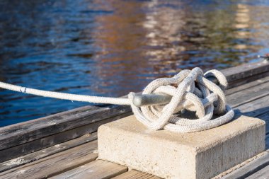 Güneşli bir sonbahar gününde, bir limanda, ahşap bir iskelede düğümlenmiş bir halata bağlanmış bir halat. Dorset, on, Kanada.