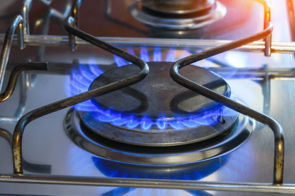 Close up of a gas ring on a kitchen hob with blue natual gas flames. Natural gas price concept.