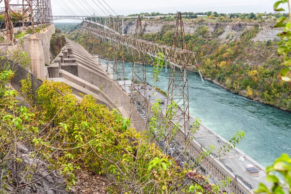 Bulutlu bir sonbahar gününde dar bir vadinin dibinde akan bir nehir boyunca hidroelektrik santrali. Niagara Şelalesi, On, Kanada.