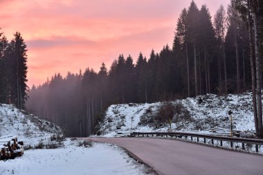 Dağlardaki boş bir orman yolunda güzel bir kış günbatımı