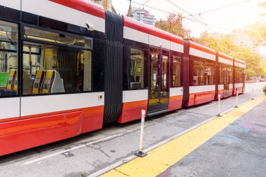 Şehir merkezindeki bir cadde boyunca tramvay durağından ayrılan boş modern tramvay. Toronto, On, Kanada,