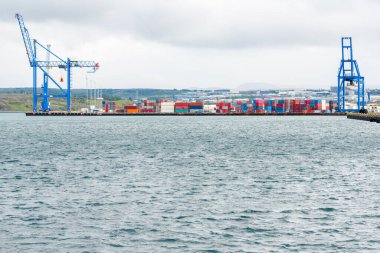 Bulutlu bir günde ıssız bir limandaki ticari bir rıhtımda renkli konteynırlar. Reykjavik, İzlanda.