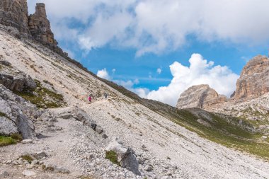 Yürüyüşçüler, güneşli bir sonbahar gününde Avrupa Alplerinde engebeli bir dağ yolunda