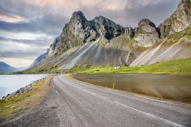 Issız, dolambaçlı bir sahil yolu, yüksek dağların eteklerinden geçiyor.