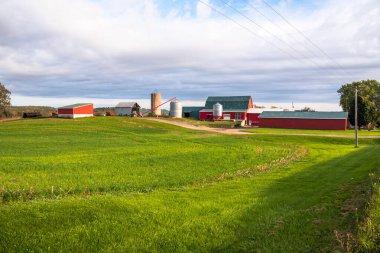 Sonbaharda sıcak günbatımında Ontario kırsalında siloları ve kırmızı ahırı olan geleneksel çiftlik.