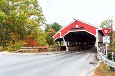 New England 'da geleneksel kırmızı kaplama köprü bulutlu bir sonbahar gününde. Jackson, NH, ABD.