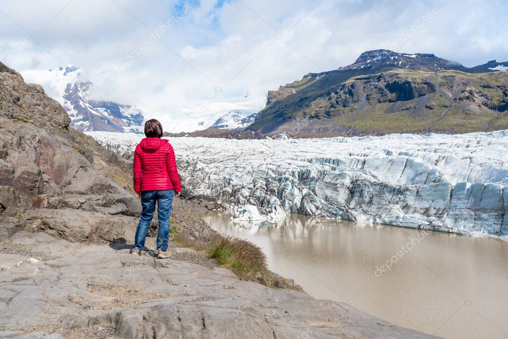Woman hiker standing in front of a majestic icefield in Iceland on a sunny summer day. Vatnajokull, Iceland.