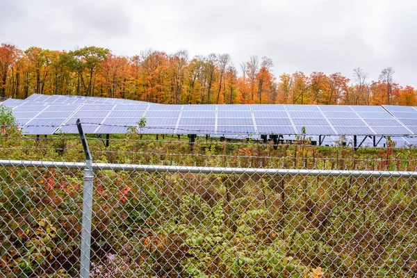 在多云的天气里 山坡上的太阳能发电厂背负着五彩缤纷的秋树 可再生能源概念 — 图库照片