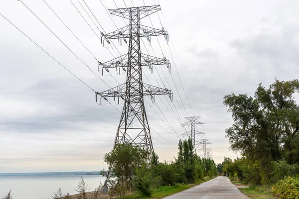 Wysokie Słupy Elektryczne Wzdłuż Opuszczonej Ścieżki Nad Jeziorem Pochmurny Dzień — Zdjęcie stockowe