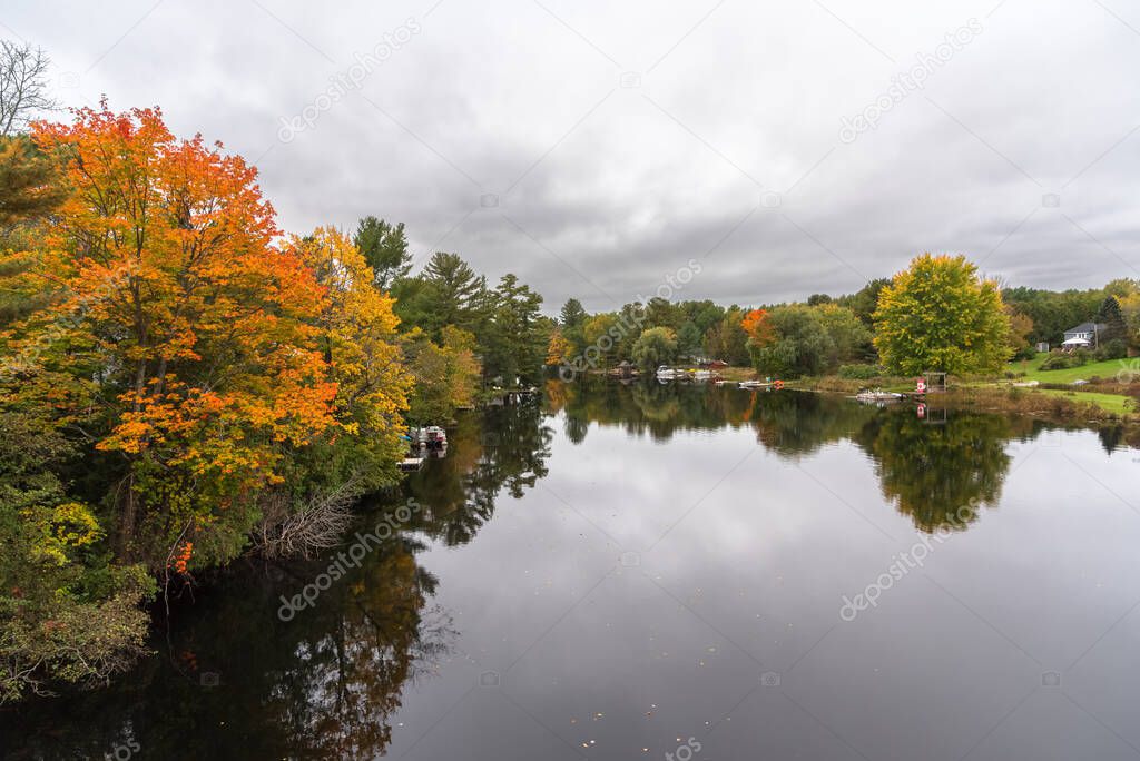 Beautiful lake with forested shores under cloudy sky in autumn. Reflection in water, Ontario, Canada.