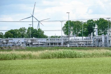 Natural gas extraction site with wind turbines in background. Groningen gas field, the Netherlands.