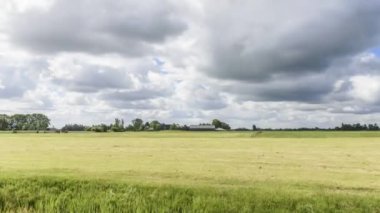 Moving clouds over a farm with horses grazing in a field - Groningen, Netherlands- time lapse