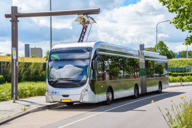 Güneşli bir yaz gününde şarj istasyonunda elektrik otobüsü. Groningen, Hollanda.