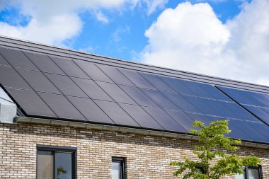 Çatıda güneş panelleri ile kaplı tuğlalı teraslı evler var. Groningen, Hollanda.