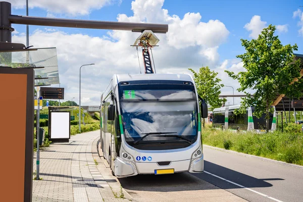 Electric bus being recharged at a suburban bus station on a clear summer day. Groningen, Netherlands.