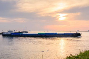 Yük mavnası gün batımında limana açılacak. Rotterdam, Hollanda.