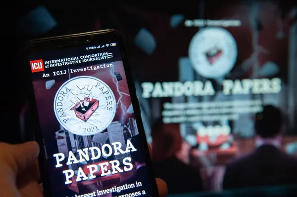 Kyiv, Ukrayna, 07 Ekim 2021. Bu resimde Pandora Papers logosu mobil ekran önplanı ve bilgisayar ekranı arka planında. 