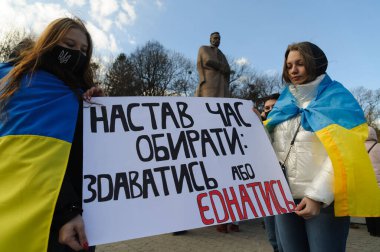 Lviv, Ukrayna, 19 Şubat 2022. Ukrayna 'nın merkezi Lviv' deki Birleşme Yürüyüşü sırasında Ukrayna-Rusya sınırındaki gerginlikler arasında 'Teslim olma ya da Birleşme Zamanı' başlıklı pankart halkın elinde..
