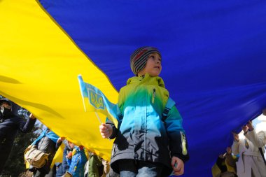 Lviv, Ukrayna, 19 Şubat 2022. Ukrayna bayrağı altında Ukrayna bayrağı taşıyan küçük çocuk Ukrayna-Rusya sınırında gerginlik ortamında Ukrayna için düzenlenen Birlik Yürüyüşü 'ne katıldı..