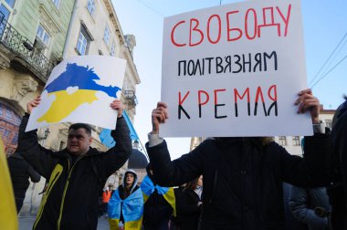 Lviv, Ukrayna, 19 Şubat 2022. Ukraynalılar, Ukrayna-Rusya sınırındaki gerginlikler ortamında Lviv şehir merkezindeki Ukrayna için Birleşme Yürüyüşüne Kırım haritası ve 'Kremlin' e Siyasi Mahkumlar İçin Özgürlük 'tabelasını taşıyorlar..