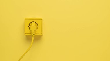 Sarı bir prize bağlı sarı bir elektrik kablosu. Şık tasarım. Elektrikli aletlerin bağlı olduğu yer..