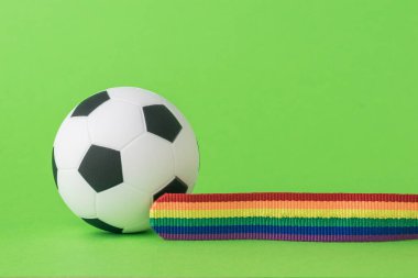 Yeşil arka planda futbol topu ve LGBT bandı. Futbolda LGBT kavramı. Metin için boşluk.