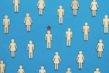 Bir grup oyulmuş ahşap adam ve mavi arka planda yıldız olan bir insan lider. İş fikri.