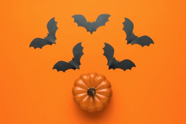 Turuncu zemin üzerinde uçan yarasalar olan seramik bir balkabağı manzarası. Popüler bir Ekim tatili. Düz yatıyordu.