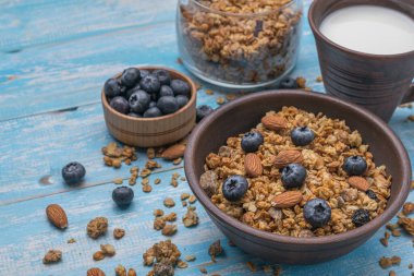 Ahşap bir masada yaban mersini ve fındıklı çamur kasesinde müsli. Sağlıklı vejetaryen kahvaltısı.