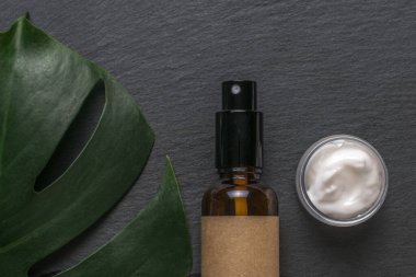 Sprey tabancalı bir şişe, bir kavanoz krema ve arka planda bir kutu canavar. Doğal terapi ve kozmetik konsepti. Düz yatıyordu.