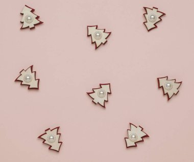 Bej arka plana saçılmış köknar ağaçlarının küçük ahşap figürleri. Yeni yılın asgari konsepti. Noel ağacı. Çağdaş sanat.