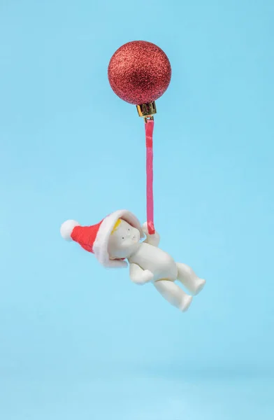 Figurka Dítěte Červené Čepici Letící Vánočním Míči Minimalismus Koncept Nového — Stock fotografie