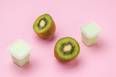 Dilimlenmiş kivi ve pembe arka planda bir fincan kivili yoğurt. Tropik meyveler.
