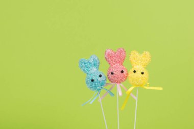 Yeşil arka planda üç renkli Paskalya tavşanı. Paskalya tatili kavramı.