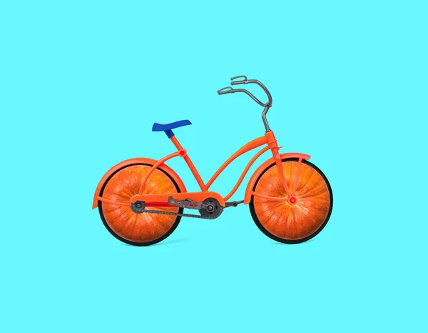 青い背景にカボチャ型の車輪が付いたオレンジの自転車 健康的なライフスタイルの概念 — ストック写真