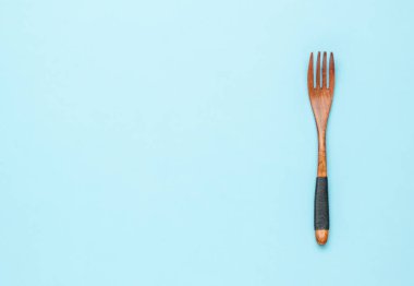 Vintage wooden fork with rope on the handle on a blue background. A place for your text.