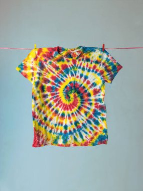 Spiral pattern on a T-shirt hanging on a clothesline. Tie dye. clipart