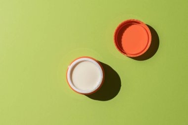An open jar with cosmetic cream on a green background. A skin care product.