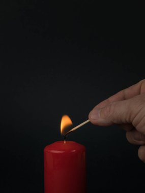 Adamın biri siyah arka planda kibritle kırmızı mum yakıyor. Romantik ilişki kavramı.