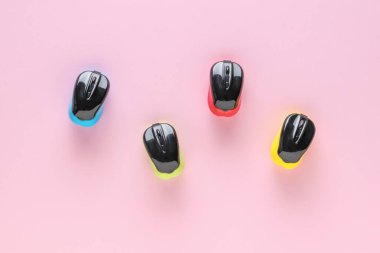 Açık pembe arka planda çok renkli bilgisayar fareleri. Kablosuz bilgisayar aksesuarları konsepti.