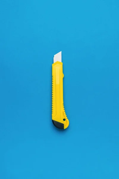 Foto Eines Minimalistischen Designs Eines Gelben Schreibwarenmessers Auf Blauem Hintergrund — Stockfoto