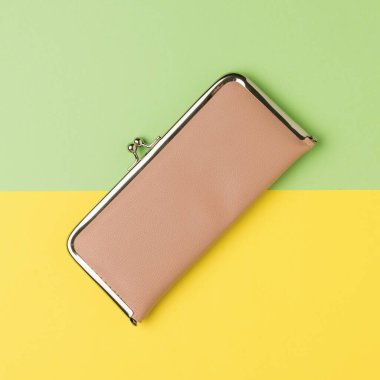 Sarı ve yeşil arka planda açık bej bir cüzdan. Aile bütçesi kavramı. Düz yatıyordu. Metin için yer.