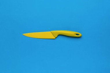 Parlak mavi arka planda parlak sarı mutfak bıçağı. Şık bıçakların merkezi bileşimi. Düz yatıyordu.
