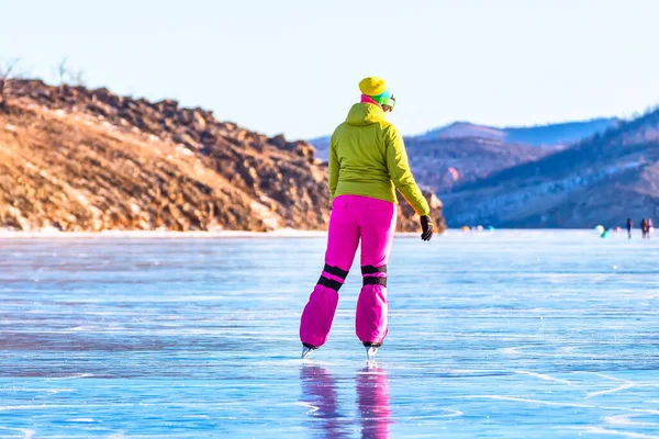 Feet close-ups of skates on legs A brightly colored dressed woman on the blue ice of Lake Baikal — Stock Photo, Image